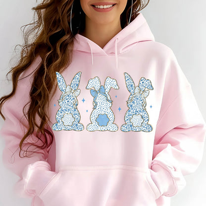 May include: Pink hoodie with a graphic of three blue bunnies with gold glitter accents. The bunnies are wearing bows and have a floral pattern.