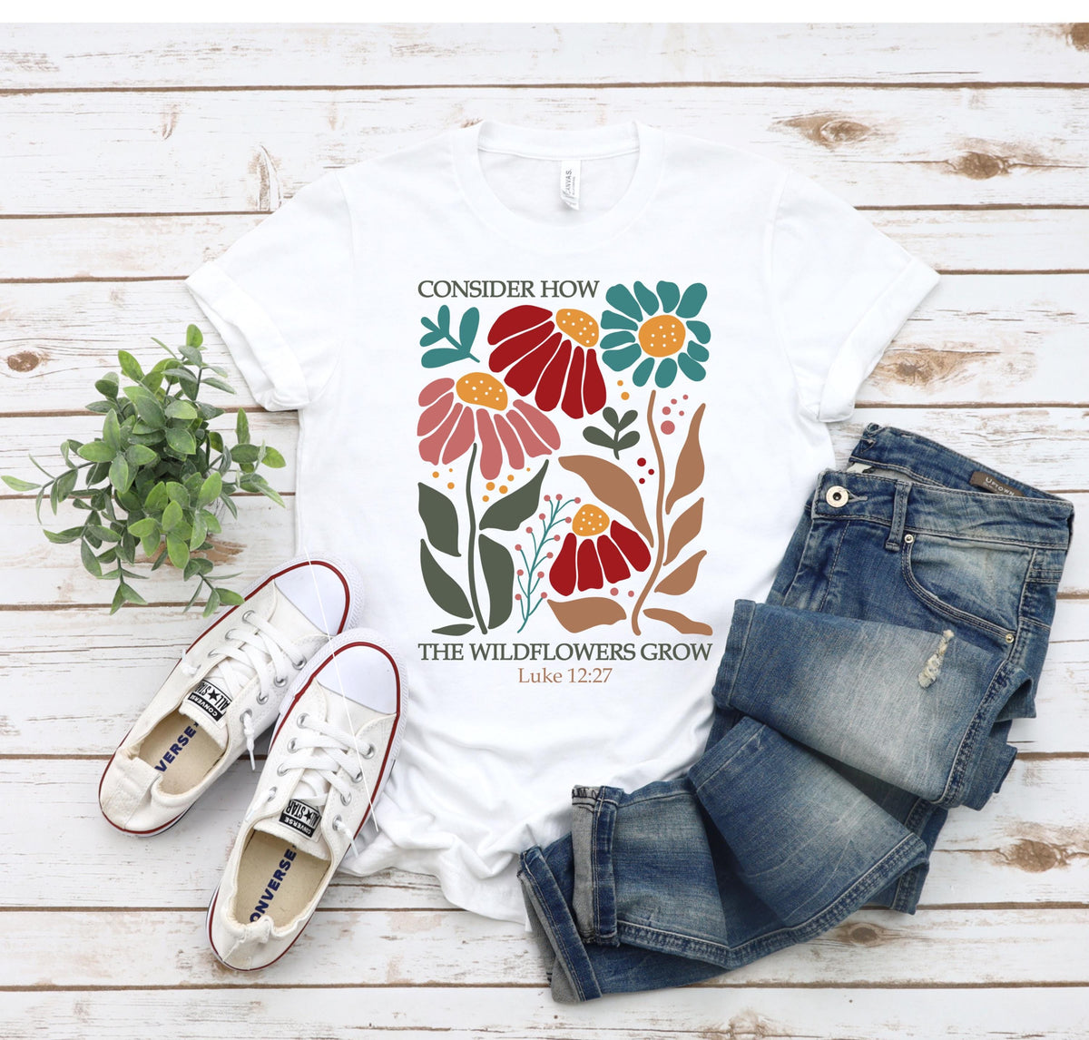 May include: White t-shirt with a floral design and the text "Consider how the wildflowers grow Luke 12:27".