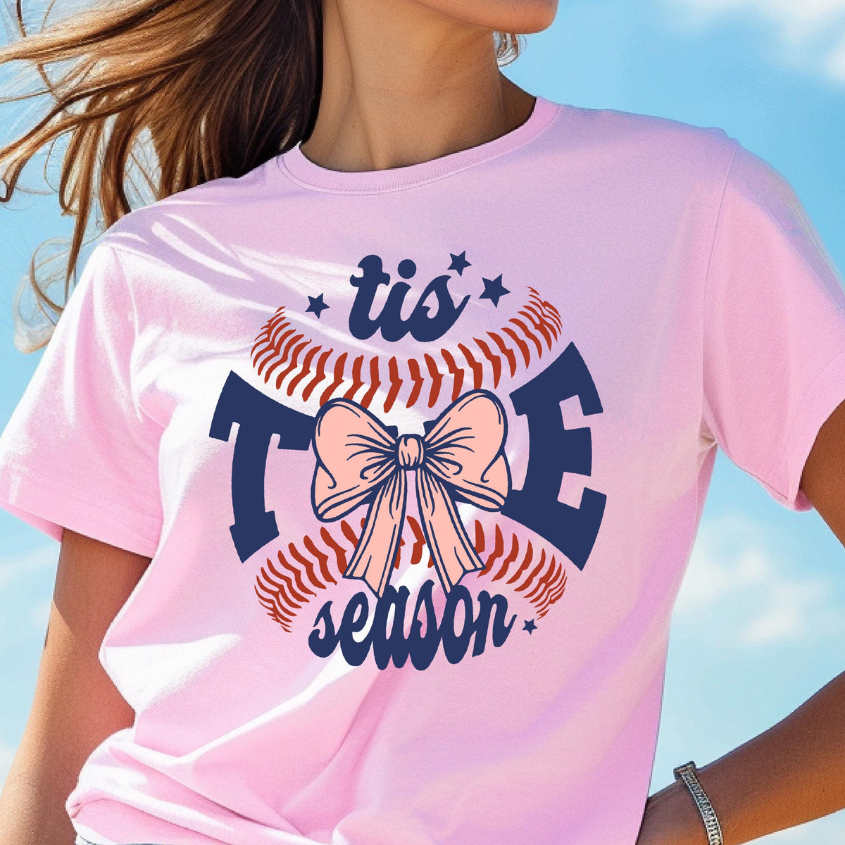 May include: Pink t-shirt with a baseball graphic and the text "tis the season" in navy blue. The baseball has a pink bow on it.