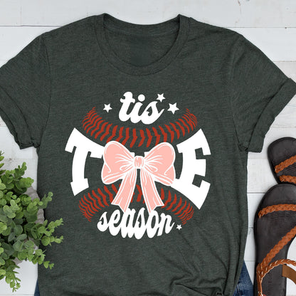 May include: A dark green t-shirt with a white baseball graphic and the text "tis the season" with a pink bow in the center.