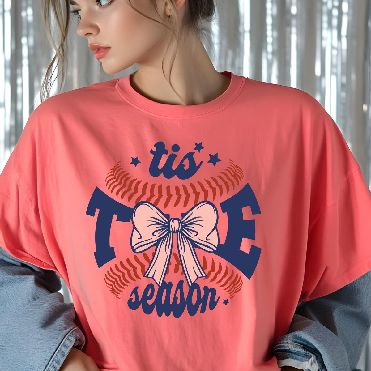 May include: A pink t-shirt with a baseball graphic and the text "tis the season" in navy blue. The baseball graphic features a pink bow.