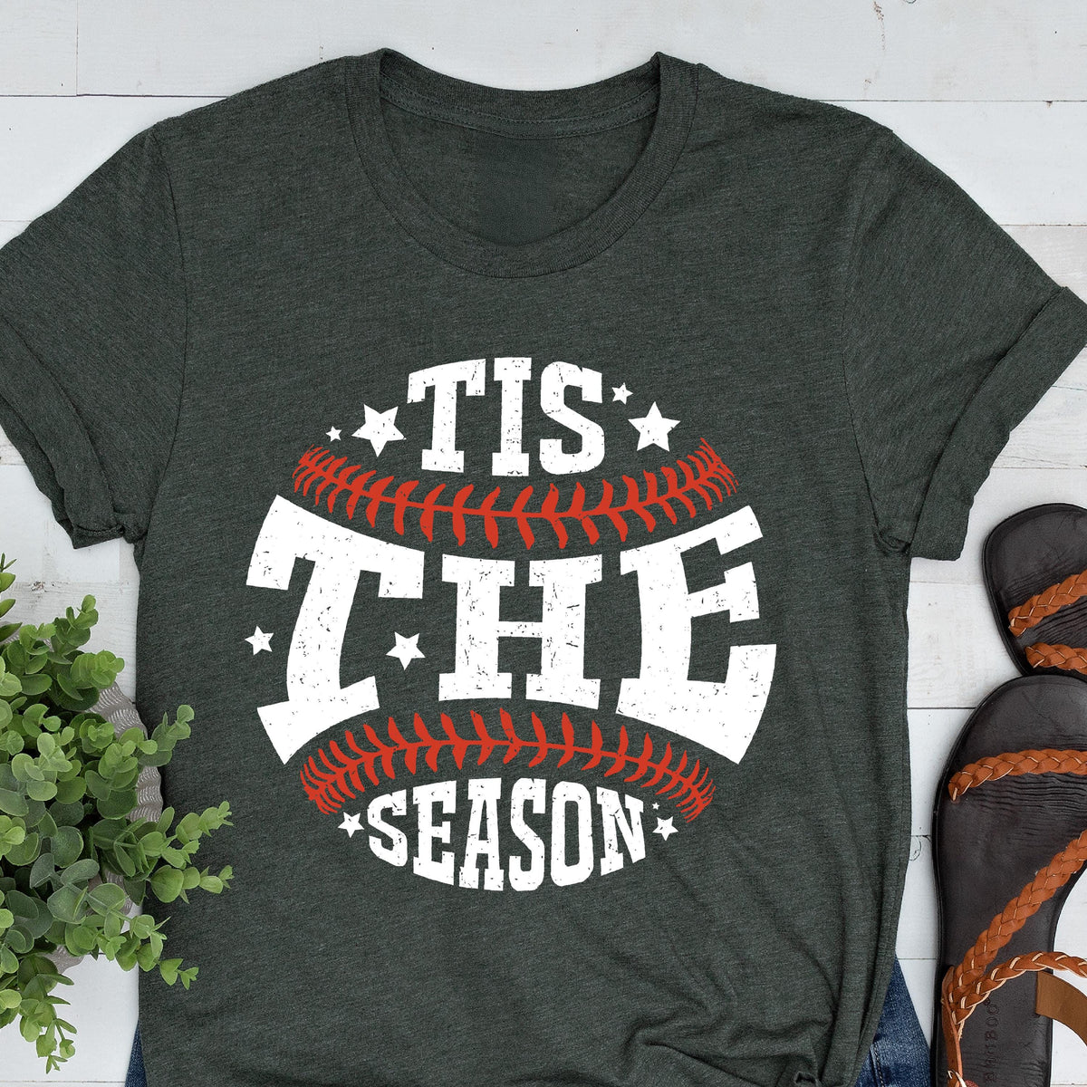 May include: A dark green t-shirt with a white baseball graphic that says "Tis the Season" on it.