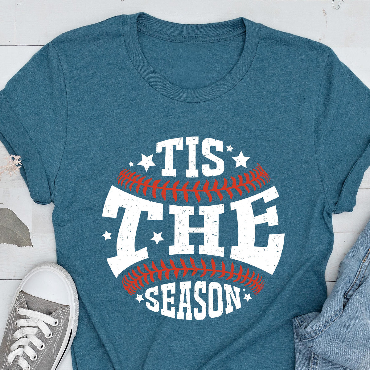 May include: A teal blue t-shirt with a white graphic of a baseball with the text "Tis the Season" in white with red stitching.