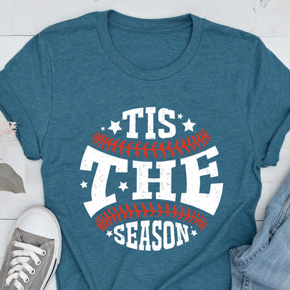 May include: A teal blue t-shirt with a white graphic of a baseball with the text "Tis the Season" in white with red stitching.