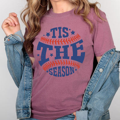 May include: A mauve t-shirt with a baseball graphic and the text "Tis the Season" in blue and red.