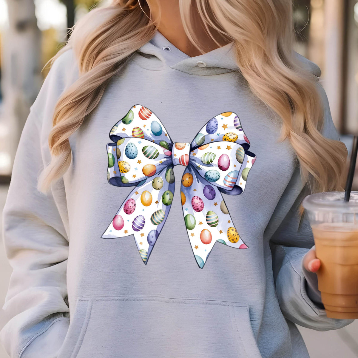 May include: A gray hoodie with a large white bow printed on the front. The bow is decorated with colorful Easter eggs.
