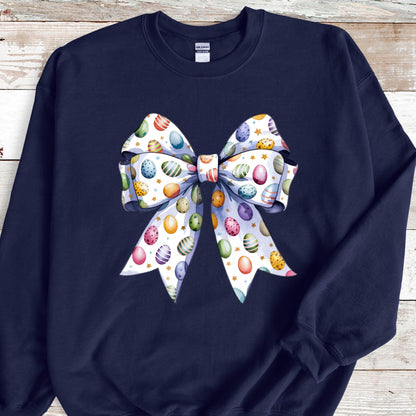May include: A navy blue sweatshirt with a white bow decorated with colorful Easter eggs. The bow is centered on the front of the sweatshirt.