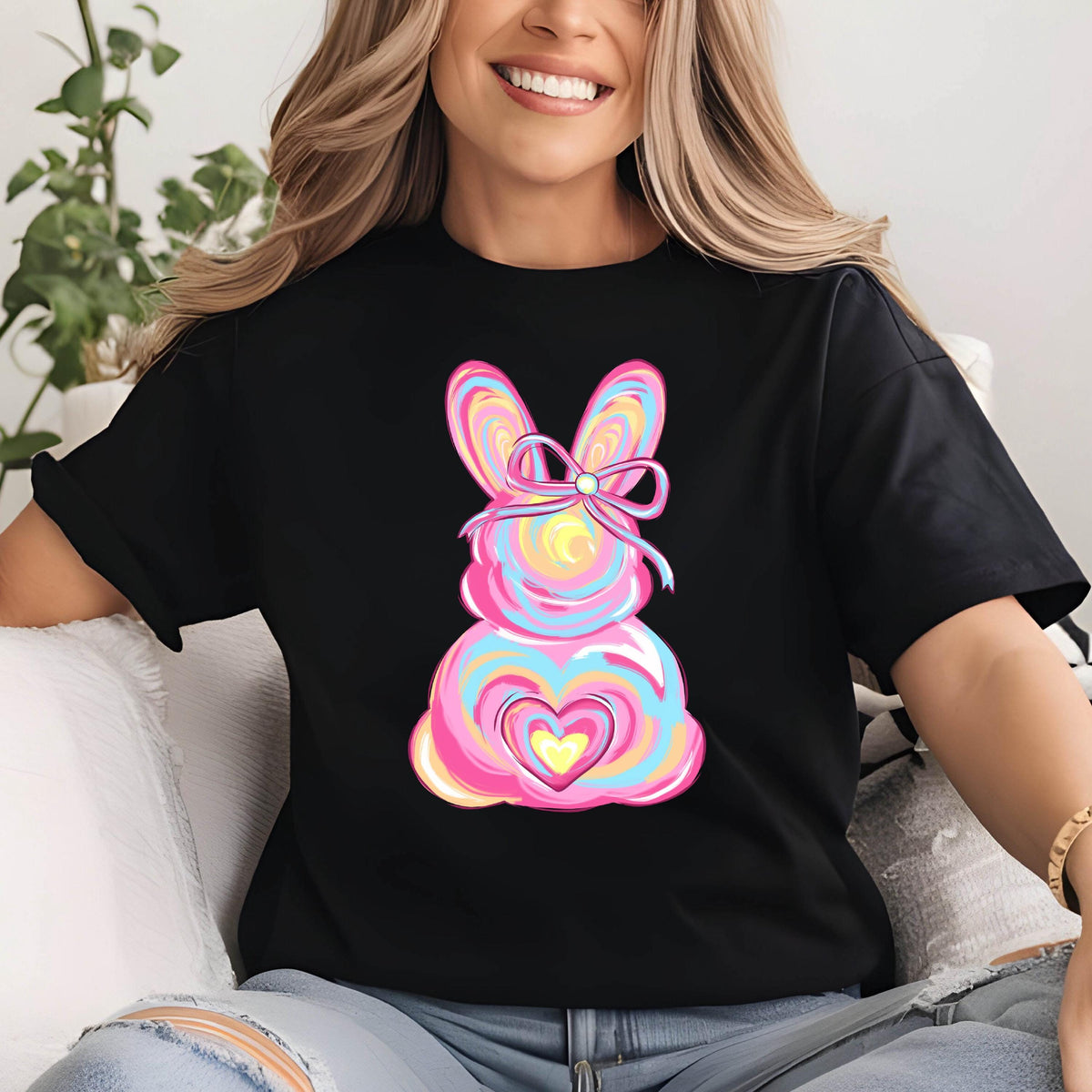 May include: A black t-shirt with a colorful Easter bunny design. The bunny is pink, blue, yellow, and white with a pink bow. The bunny has a heart in the center of its body.