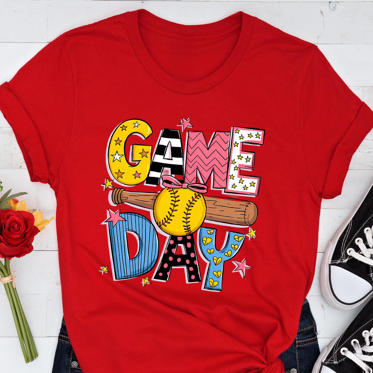 May include: Red t-shirt with a colorful graphic design that says "GAME DAY" with a softball and bat. 