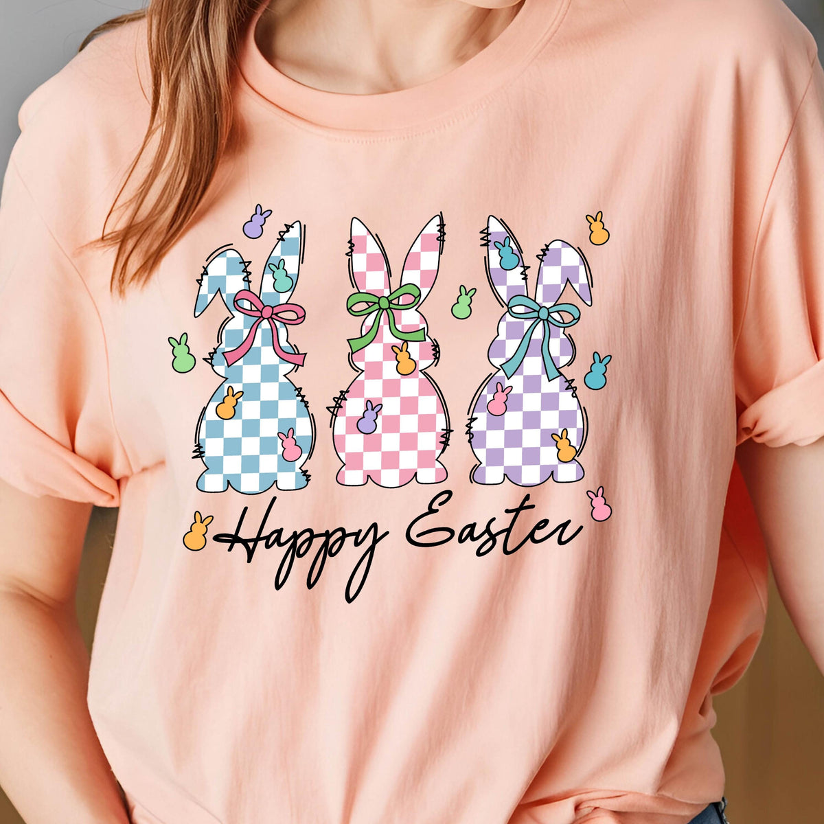 May include: A pink t-shirt with a graphic of three checkered Easter bunnies and the text "Happy Easter".