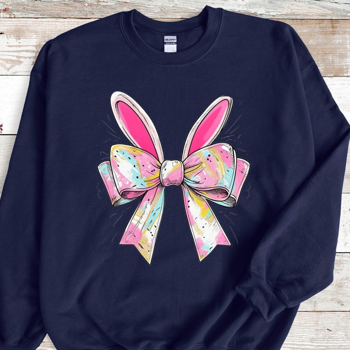 May include: A navy blue sweatshirt with a pink and white bow with bunny ears. The bow has a colorful, abstract pattern.