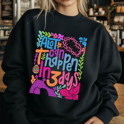 May include: Black sweatshirt with a colorful graphic design that says "A lot can happen in 3 days". The graphic includes flowers, a cross, a crown of thorns, and an Easter egg.