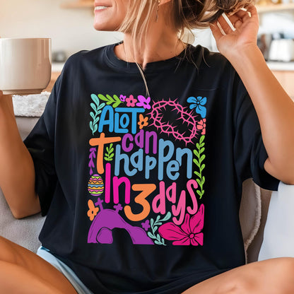 May include: Black t-shirt with a colorful graphic design that says "A lot can happen in 3 days". The graphic includes flowers, a cross, and an Easter egg.