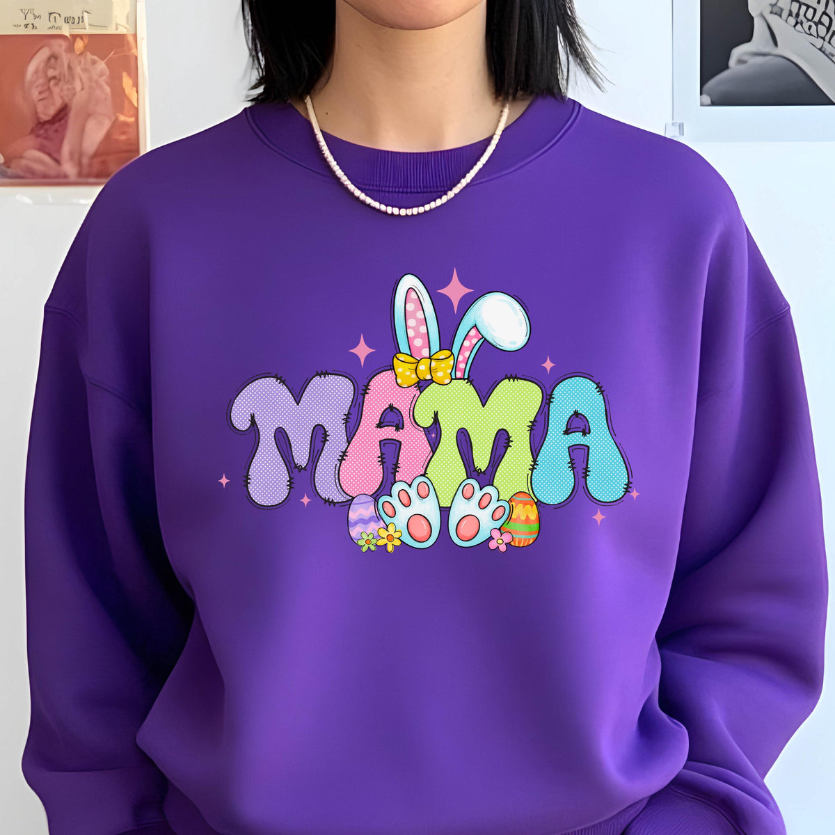 May include: Purple sweatshirt with a graphic of the word "MAMA" in colorful letters with bunny ears and Easter eggs. 