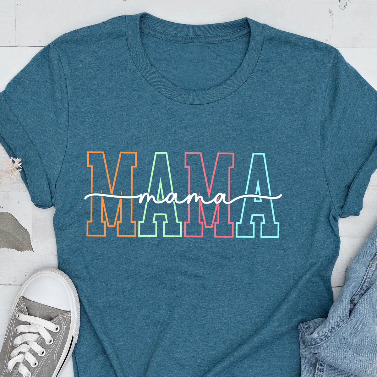 May include: A teal blue t-shirt with the word "MAMA" in rainbow colors with a white script "mama" underneath.
