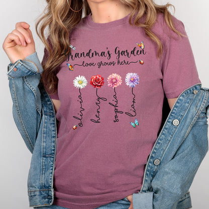 May include: A mauve t-shirt with the text "Grandma's Garden - love grows here" and four flowers with names Olivia, Henry, Sophia, and Liam written underneath each flower.