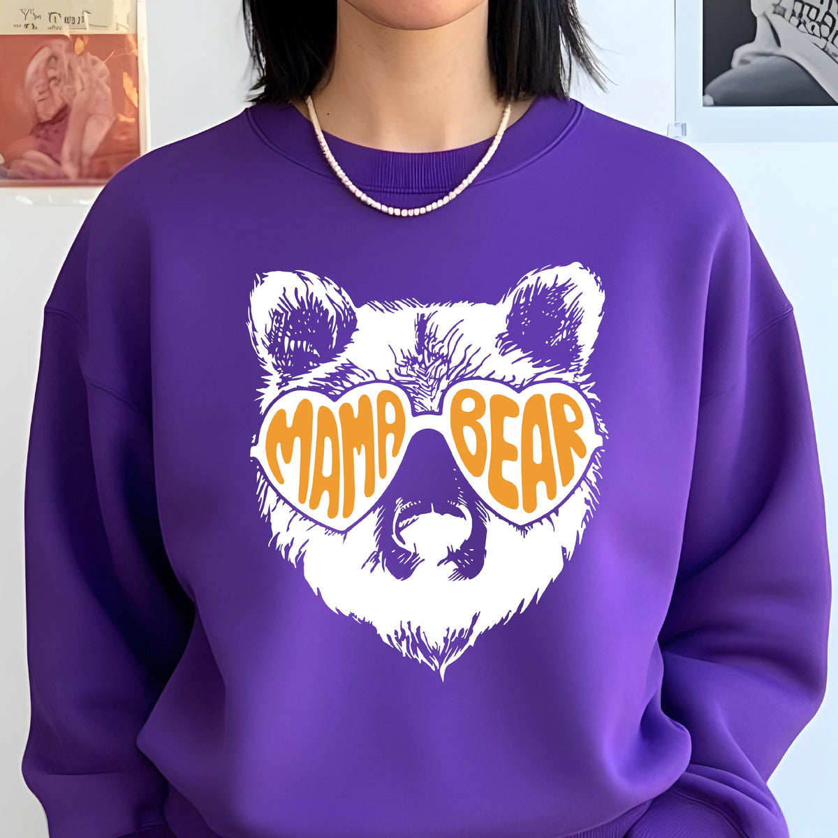 May include: Purple sweatshirt with a white bear wearing orange heart-shaped sunglasses that say "Mama Bear".