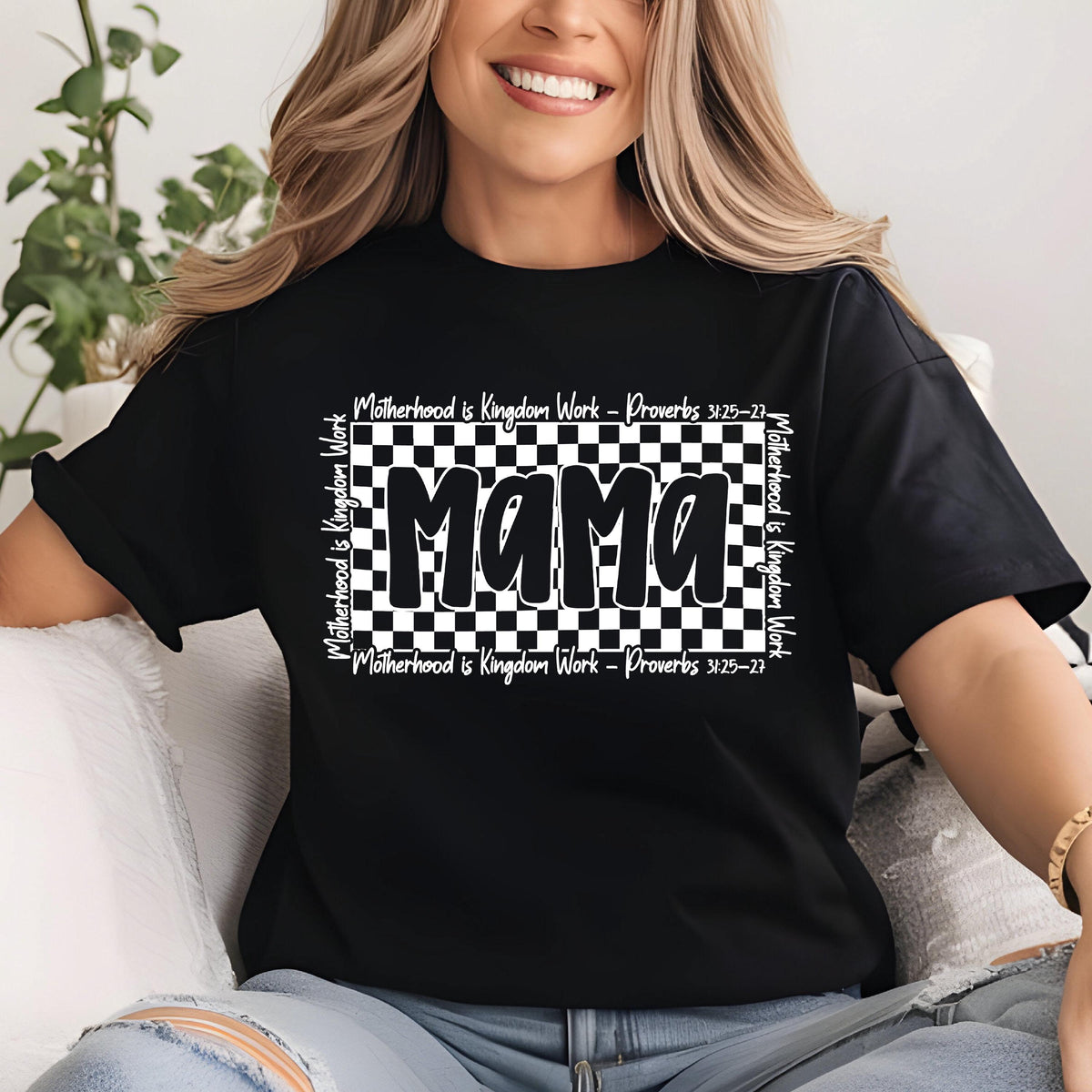 May include: Black t-shirt with a white checkered background and the word "Mama" in bold white letters. The text "Motherhood is Kingdom Work - Proverbs 31:25-27" is written in white on the top and bottom of the checkered background.
