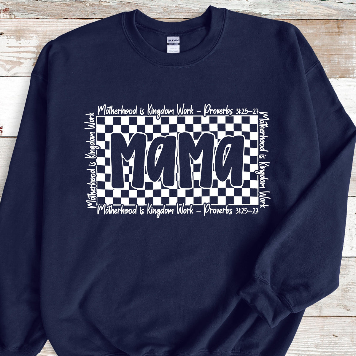 May include: Navy blue sweatshirt with a white checkered background and the word "Mama" in white. The text "Motherhood is Kingdom Work - Proverbs 3:25-27" is repeated on the top and bottom of the checkered background.