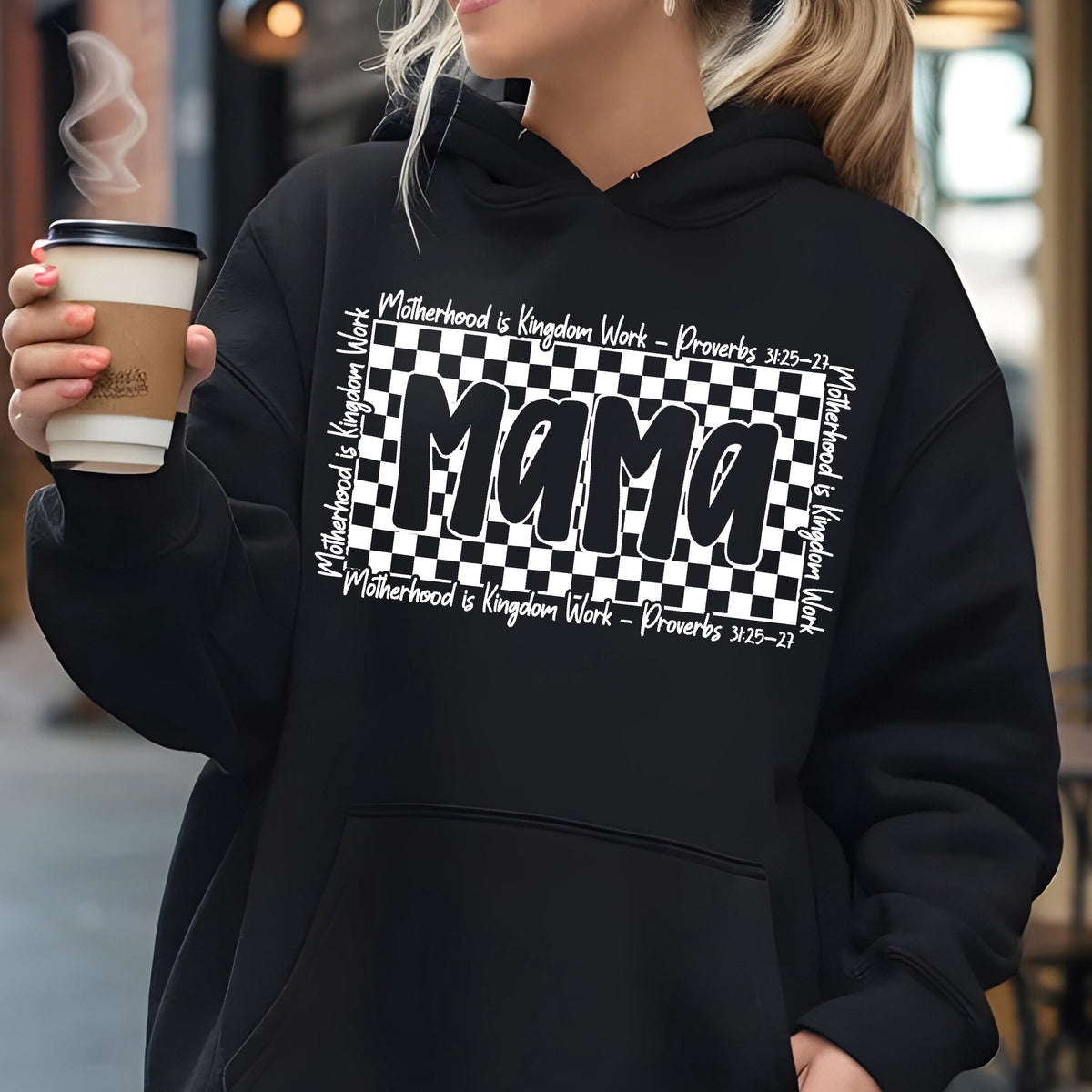 May include: Black hoodie with a white checkered design and the word "Mama" in bold white letters. The text "Motherhood is Kingdom Work - Proverbs 31:25-27" is written in white on the top and bottom of the checkered design.