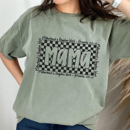May include: Green t-shirt with a black and white checkered design and the word "Mama" in a bold, black font. The text "Motherhood is Kingdom Work - Proverbs 31:25-27" is repeated around the checkered design.