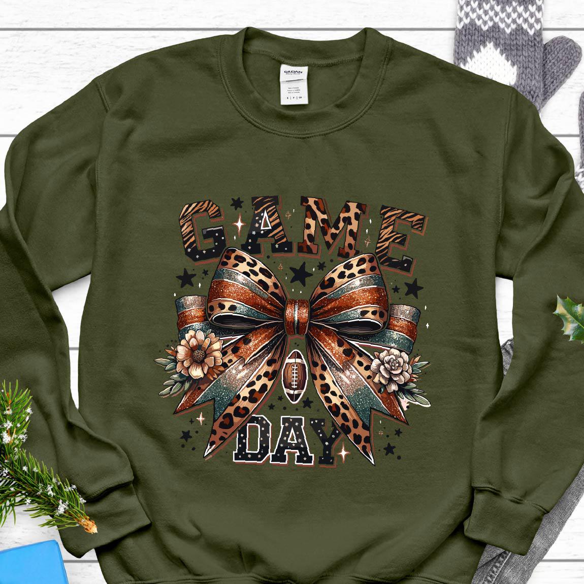 May include: A green sweatshirt with a leopard print bow and the words "GAME DAY" in a brown, black, and white font.