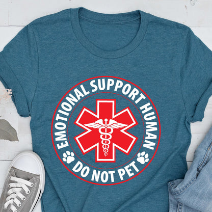 May include: Teal-colored t-shirt featuring a red and white graphic. The graphic includes a red star with a medical symbol, the words "EMOTIONAL SUPPORT HUMAN" and "DO NOT PET" in a circular design, and paw prints.