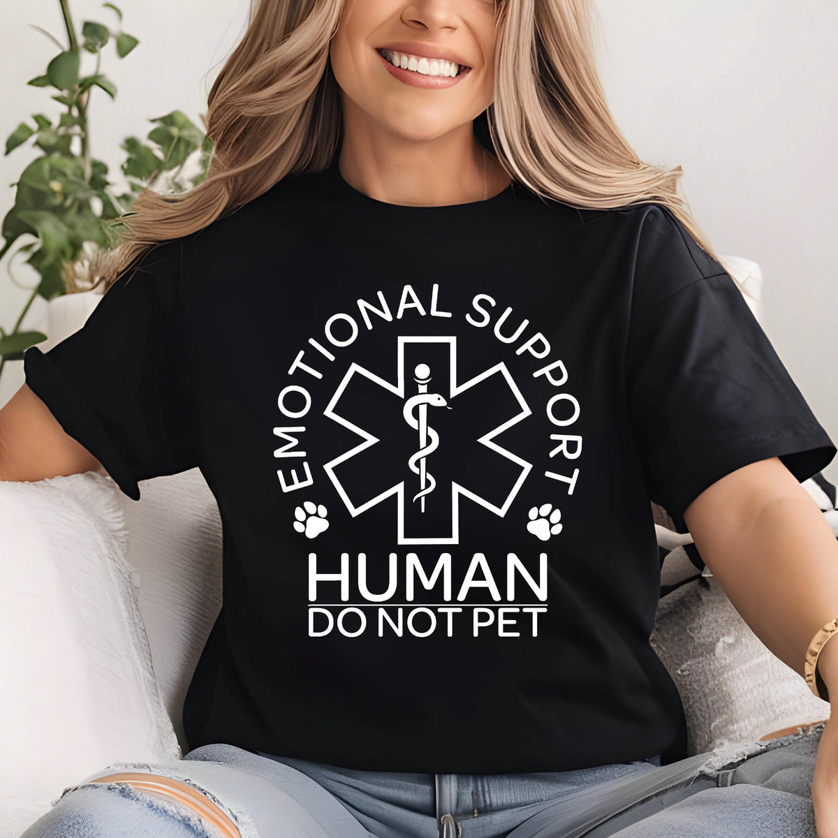 May include: A black short-sleeved t-shirt featuring a white graphic of a Star of Life symbol with a snake and staff. The text reads EMOTIONAL SUPPORT HUMAN DO NOT PET, accompanied by two small paw print icons on either side of the central emblem.