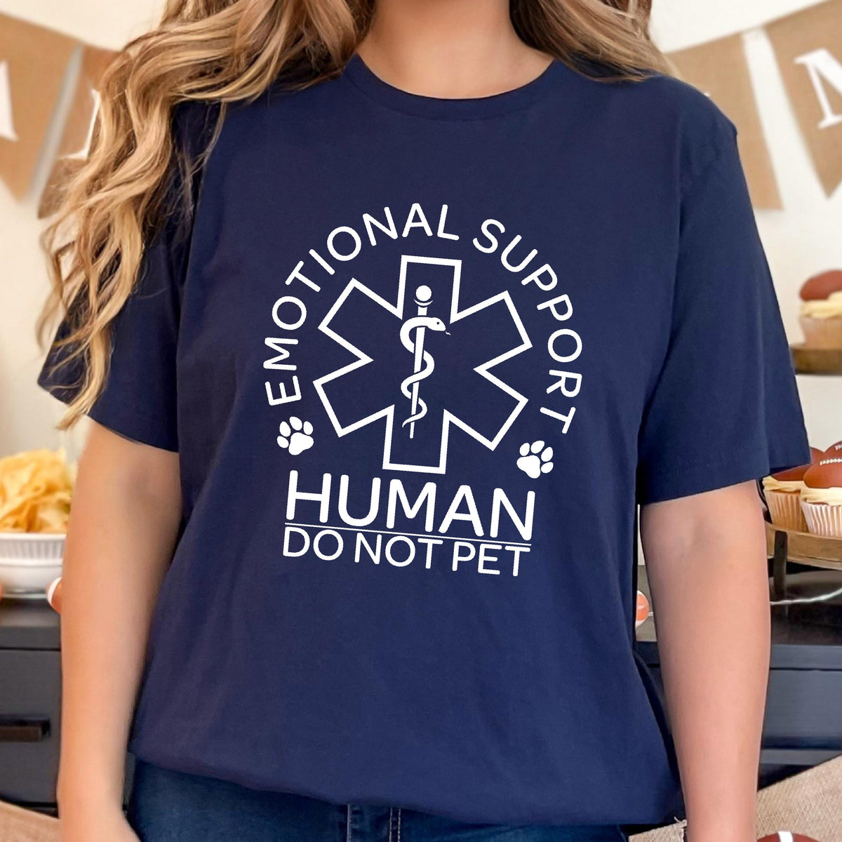 May include: A navy blue short-sleeve t-shirt featuring a white graphic of a Star of Life symbol with a snake and staff. The text reads "EMOTIONAL SUPPORT HUMAN DO NOT PET" with two small paw prints flanking the central medical emblem design.