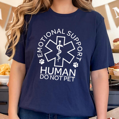 May include: A navy blue short-sleeve t-shirt featuring a white graphic of a Star of Life symbol with a snake and staff. The text reads "EMOTIONAL SUPPORT HUMAN DO NOT PET" with two small paw prints flanking the central medical emblem design.