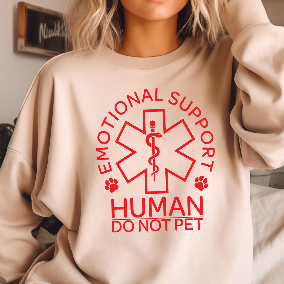 May include: A beige sweatshirt with a red graphic of a medical symbol with a snake and the text "Emotional Support Human Do Not Pet".