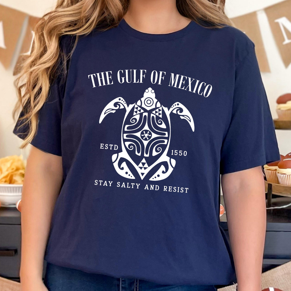 May include: A navy blue t-shirt with a white graphic of a turtle with the text "The Gulf of Mexico" above it and "Estd 1550" and "Stay Salty and Resist" below it.
