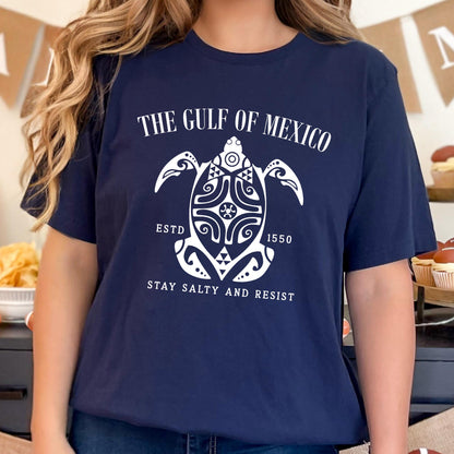 May include: A navy blue t-shirt with a white graphic of a turtle with the text "The Gulf of Mexico" above it and "Estd 1550" and "Stay Salty and Resist" below it.