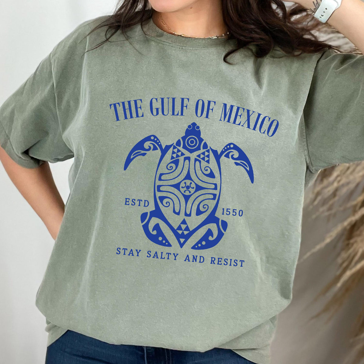 May include: A green t-shirt with a blue graphic of a turtle with the text "The Gulf of Mexico" above it and "Estd 1550" and "Stay Salty and Resist" below it.