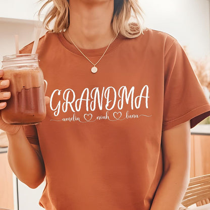 May include: A brown t-shirt with the text "Grandma" in white cursive lettering. Below the text are the names "Amelia", "Noah", and "Luna" with a heart symbol between each name.
