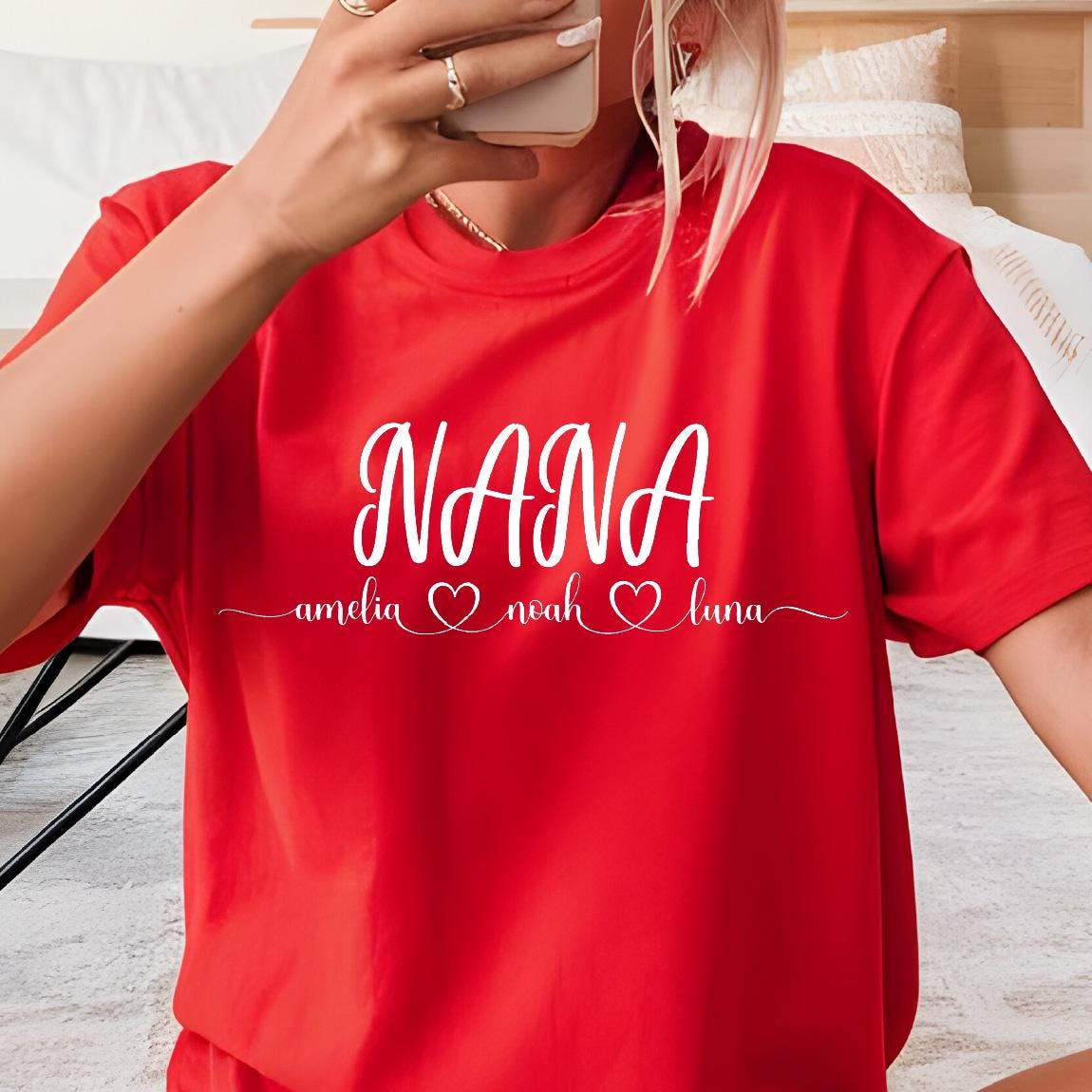 May include: Red t-shirt with white text that reads "NANA" with the names "amelia", "noah", and "luna" written below in smaller font with a heart symbol between each name.