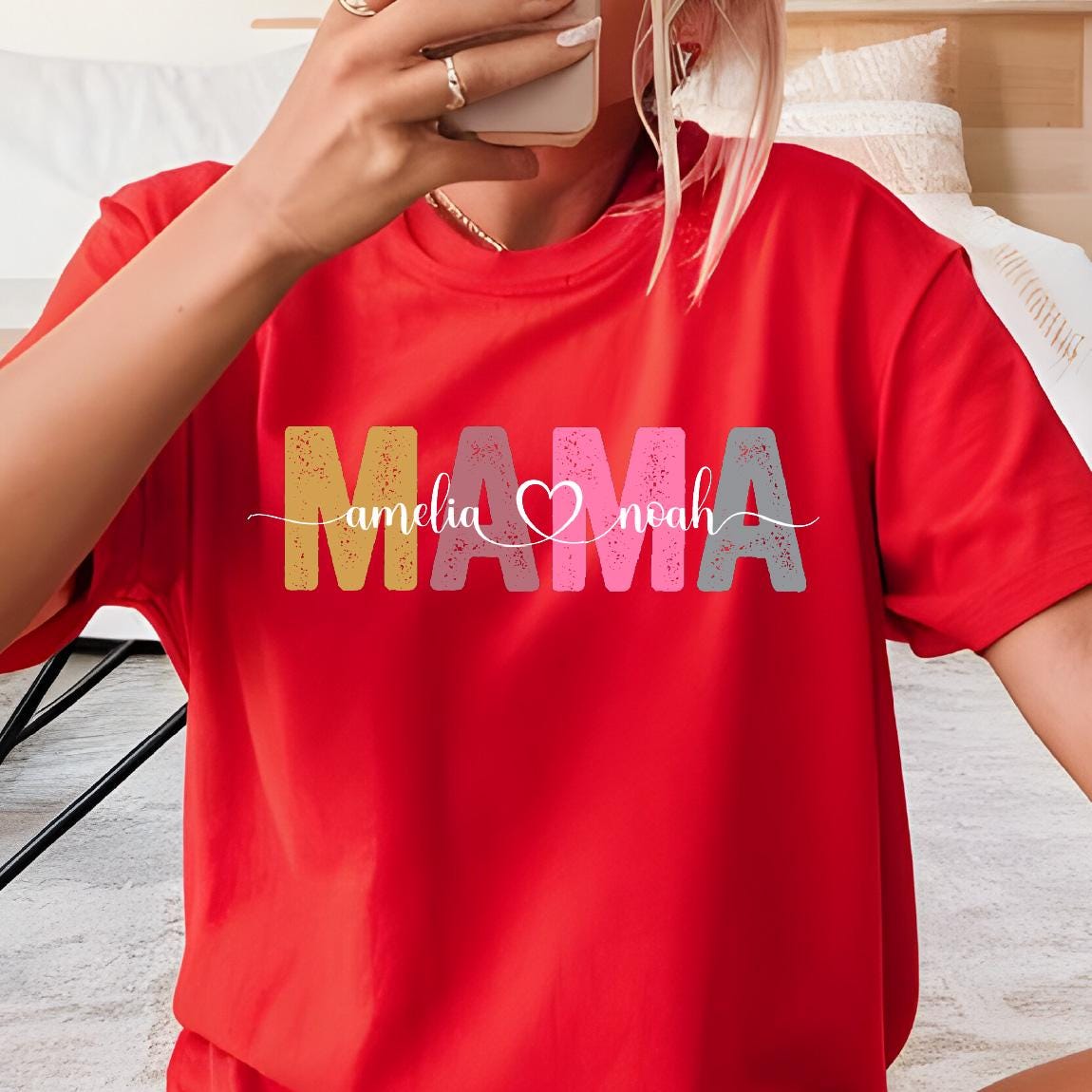 May include: Red t-shirt with the word "MAMA" in colorful letters with the names "amelia" and "noah" written on either side of the word.