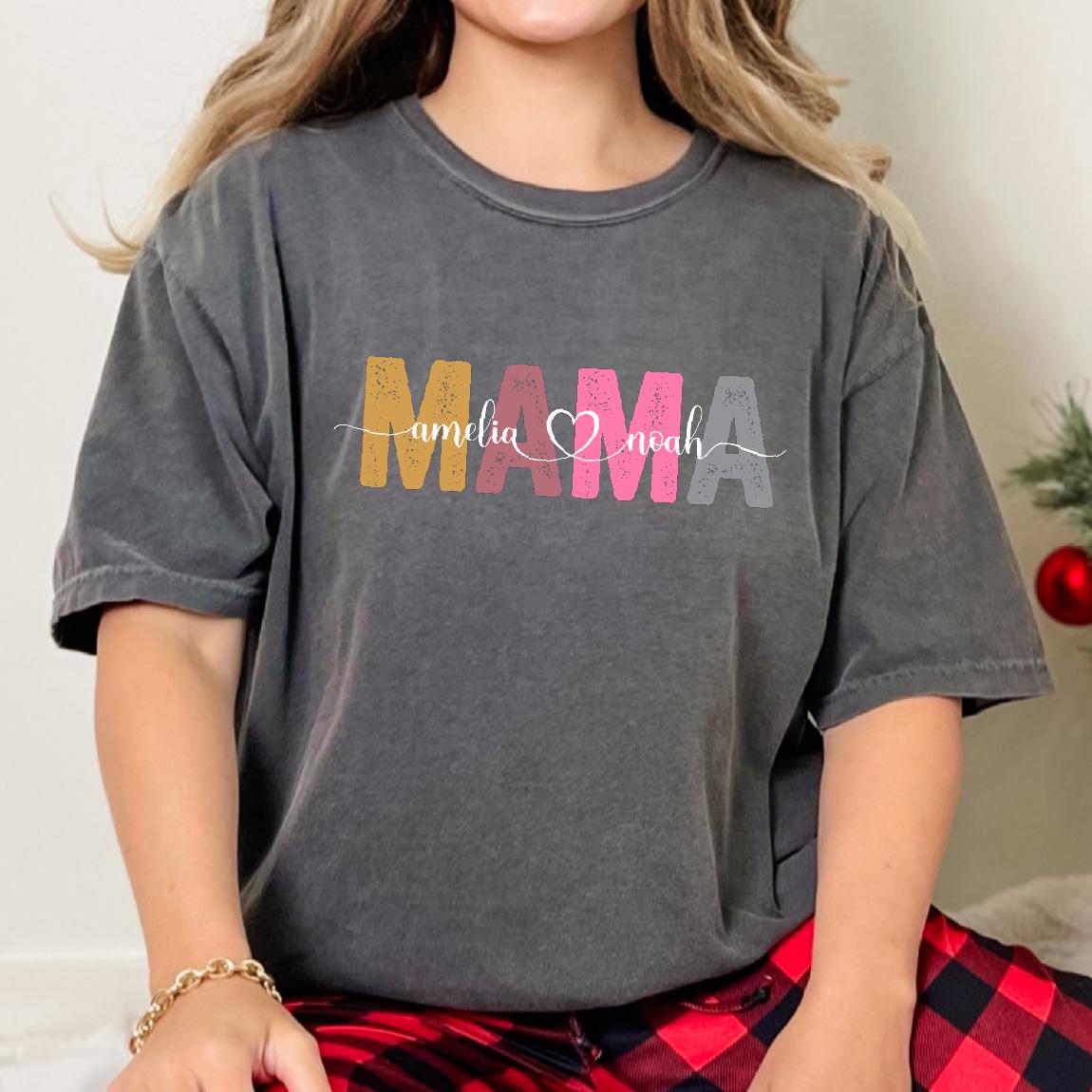 May include: A gray t-shirt with the word "MAMA" in colorful letters. The names "amelia" and "noah" are written in white script below the word "MAMA" with a pink heart symbol between the names.