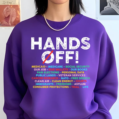 May include: Purple sweatshirt with the text "HANDS OFF!" in white with a red slash through the O in OFF. Below the text is a list of items in various colors: MEDICAID, MEDICARE, SOCIAL SECURITY, OUR JOB, OUR WALLETS, OUR BOOKS, FAIR ELECTIONS, PERSONAL DATA, PUBLIC LANDS, VETERAN SERVICES, CANCER RESEARCH, NATO, FREE SPEECH, CLEAN AIR, CLEAN ENERGY, COURTS, IMMIGRANTS, FREEDOMS, ASYLUM, CONSUMER PROTECTIONS, TRIAL, LIFE.