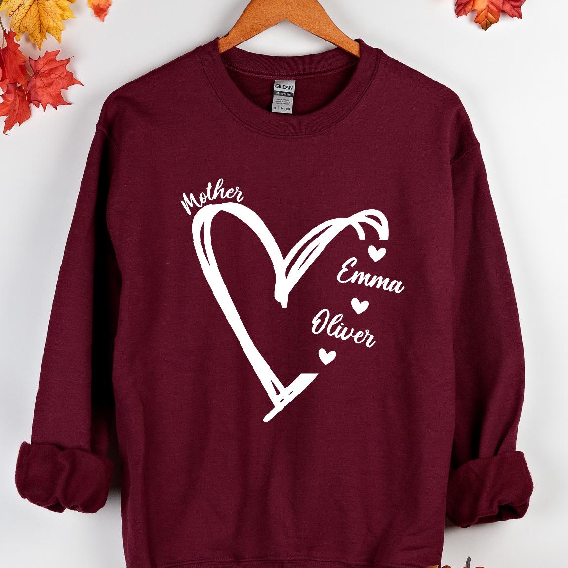 May include: Burgundy sweatshirt with a white heart design and the words "Mother", "Emma", and "Oliver" inside the heart.