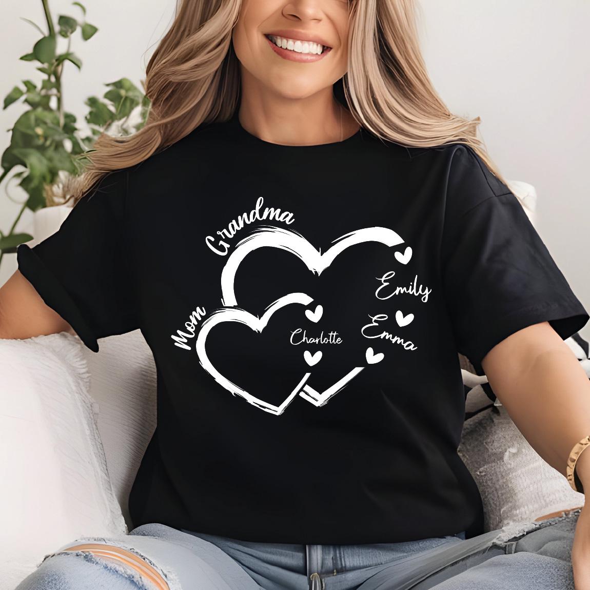 May include: Black t-shirt with a white design of two interlocking hearts. The hearts have the words "Grandma", "Mom", "Charlotte", "Emily", and "Emma" written on them.