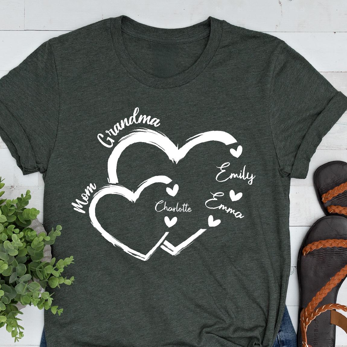 May include: A dark green t-shirt with a white design of two interlocking hearts. The hearts are labeled "Grandma", "Mom", "Charlotte", "Emily", and "Emma".