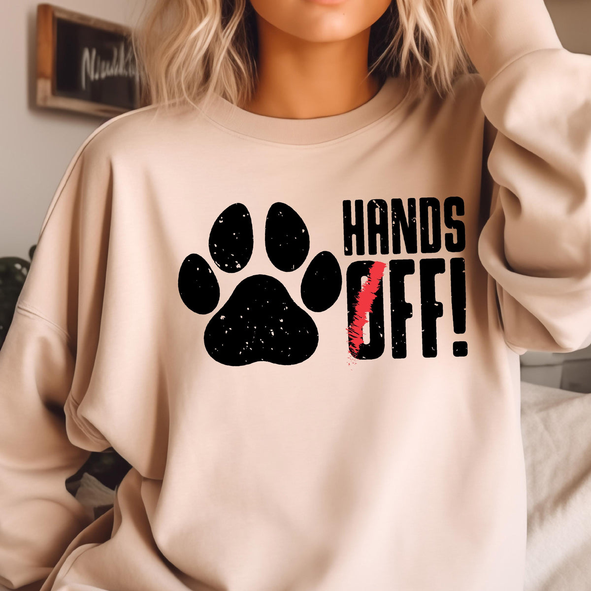 May include: A beige sweatshirt with a black paw print and the text "HANDS OFF!" in black.