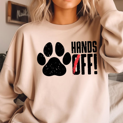 May include: A beige sweatshirt with a black paw print and the text "HANDS OFF!" in black.