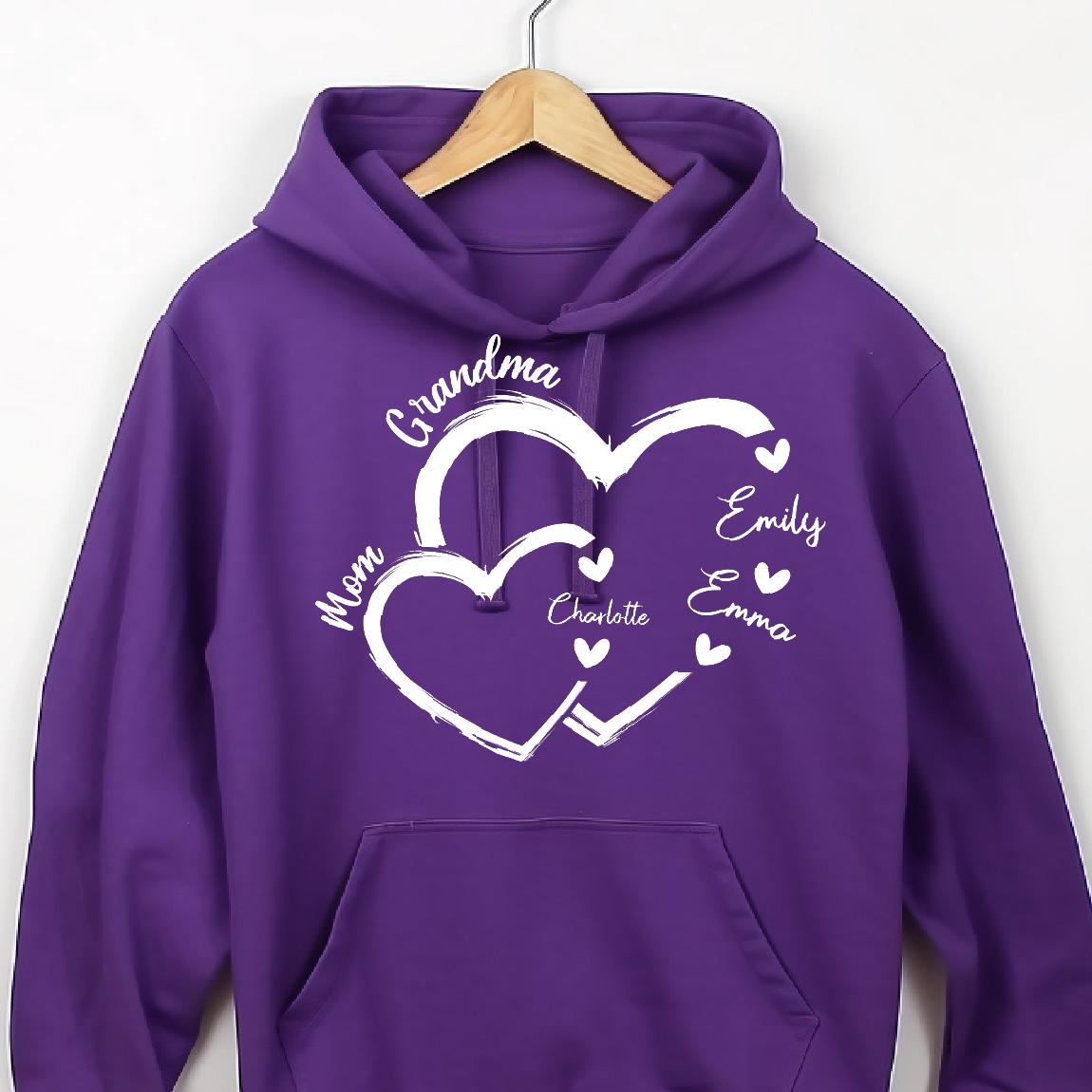 May include: Purple hoodie with a white design of two intertwined hearts. The text "Grandma" is above the hearts, and the names "Mom", "Charlotte", "Emily", and "Emma" are inside the hearts.