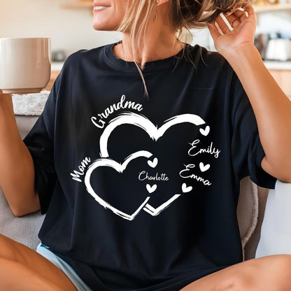 May include: Black t-shirt featuring a white heart design with the words "Grandma" and "Mom". The names "Emily", "Emma", and "Charlotte" are also displayed. The shirt is a comfortable, casual style.