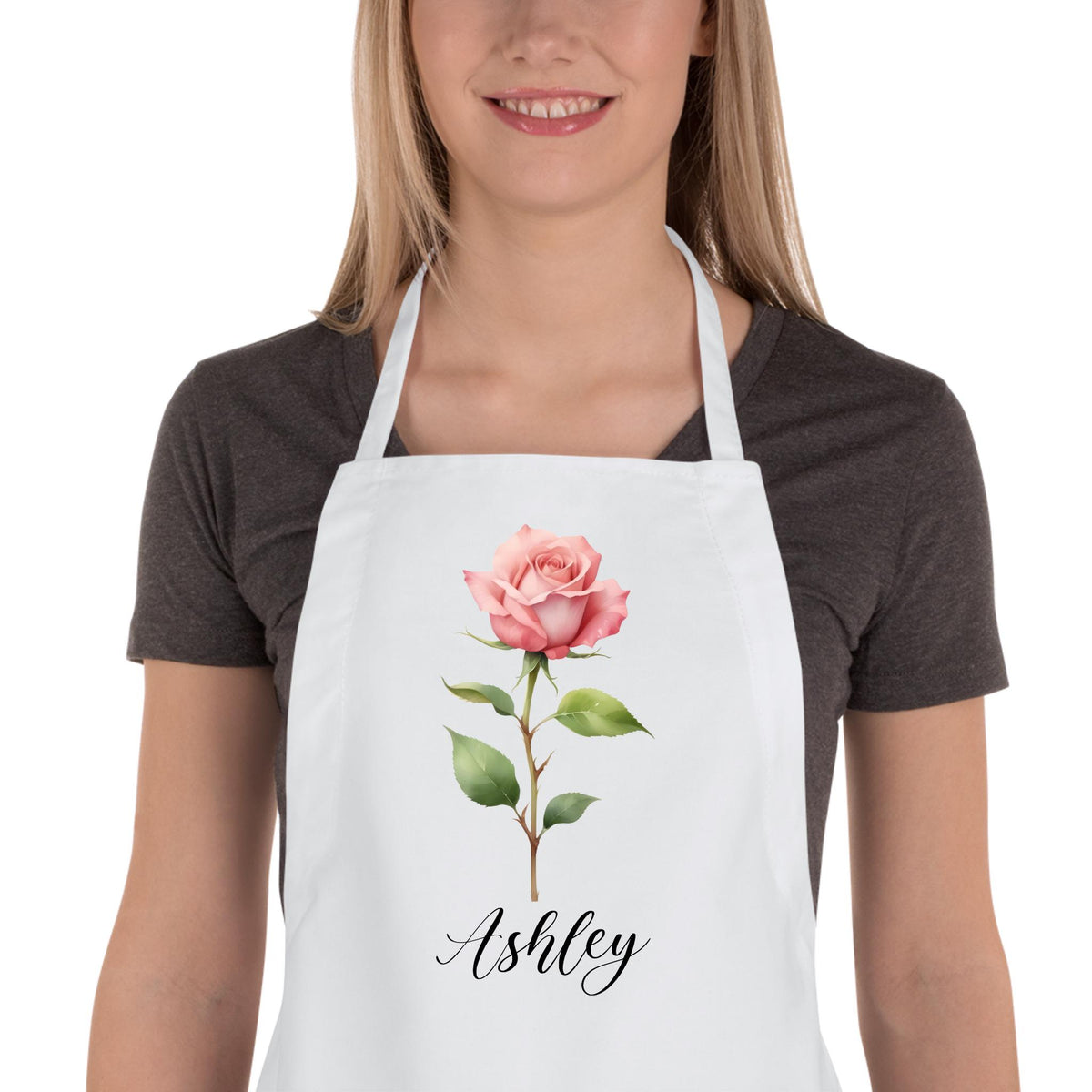 May include: White apron with a pink rose and the name Ashley printed in black cursive.