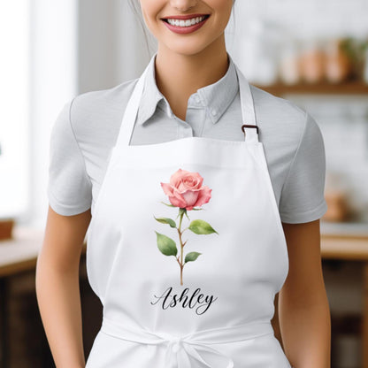 May include: White apron with a pink rose and the name "Ashley" printed on it.