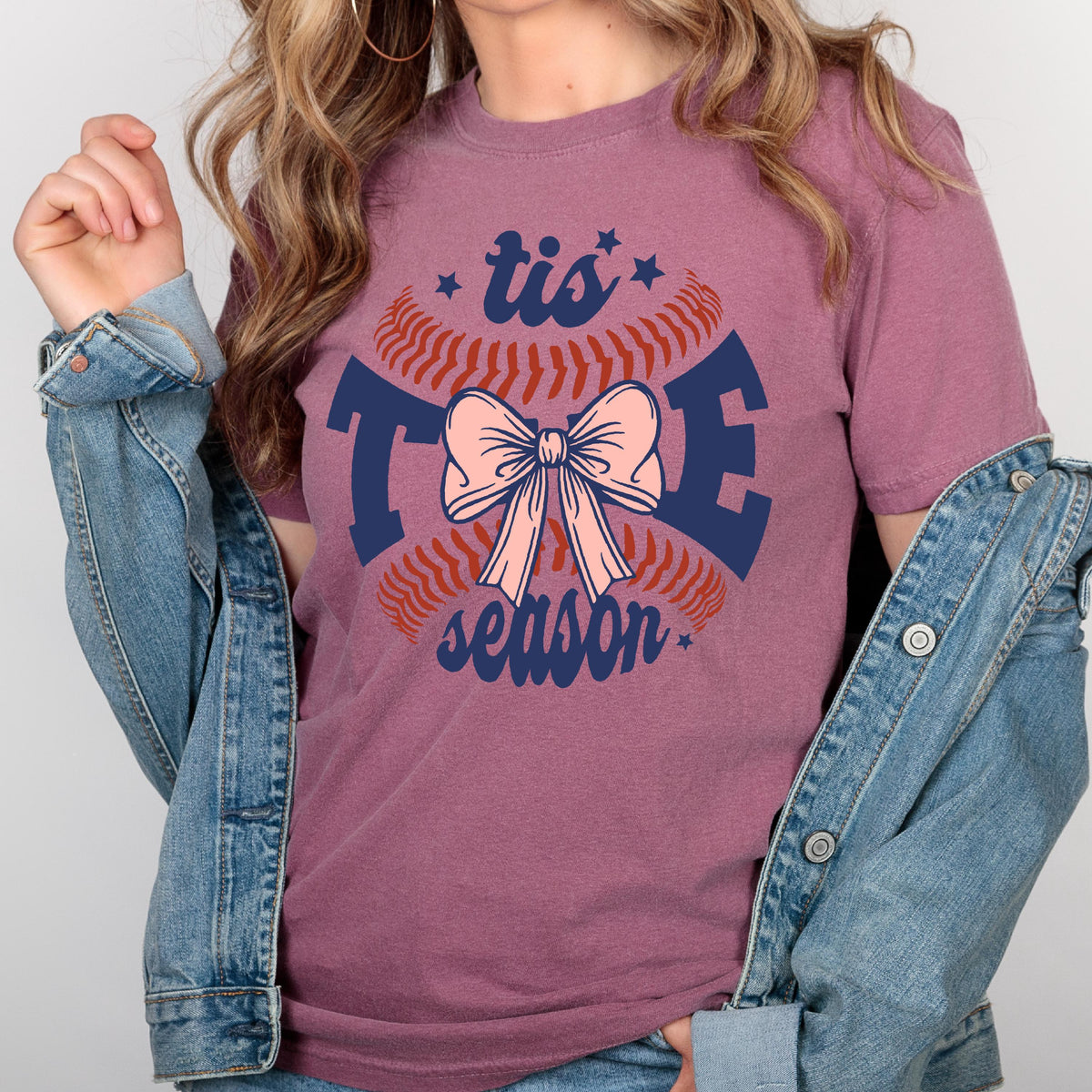 May include: A maroon t-shirt with a baseball graphic and the text "tis the season" with a pink bow in the center.