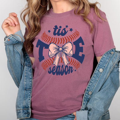 May include: A maroon t-shirt with a baseball graphic and the text "tis the season" with a pink bow in the center.